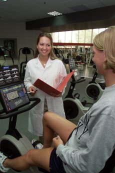 Counseling session during exercise dietitian counseling student on exercise equipment