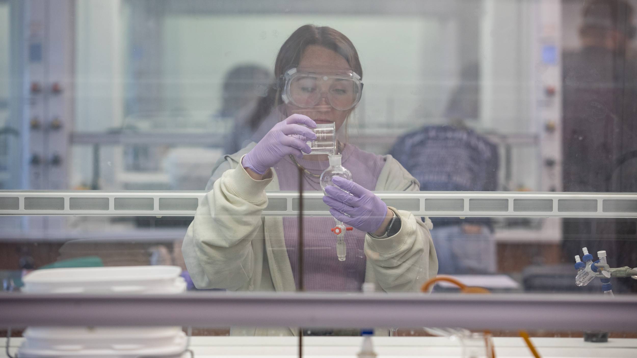 A Western Kentucky University Chemistry student pours liquid into a separatory funnel.