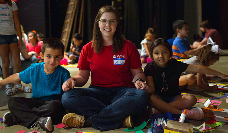 Woman holding hands with two children.