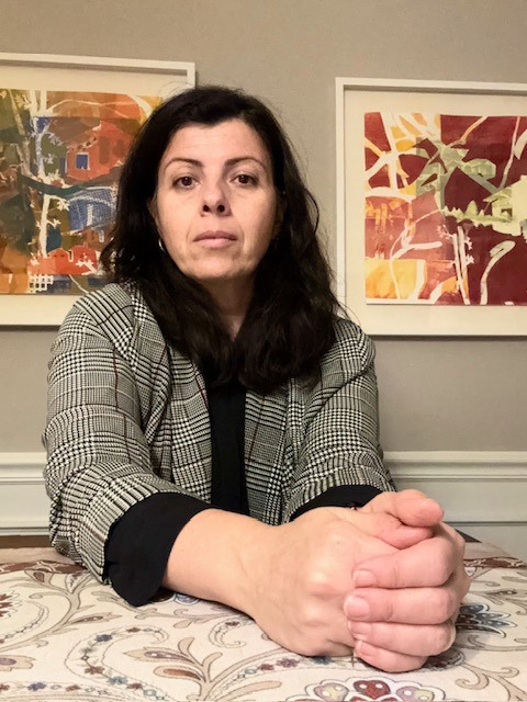 Neli Ouzounova sits in front of her paintings.