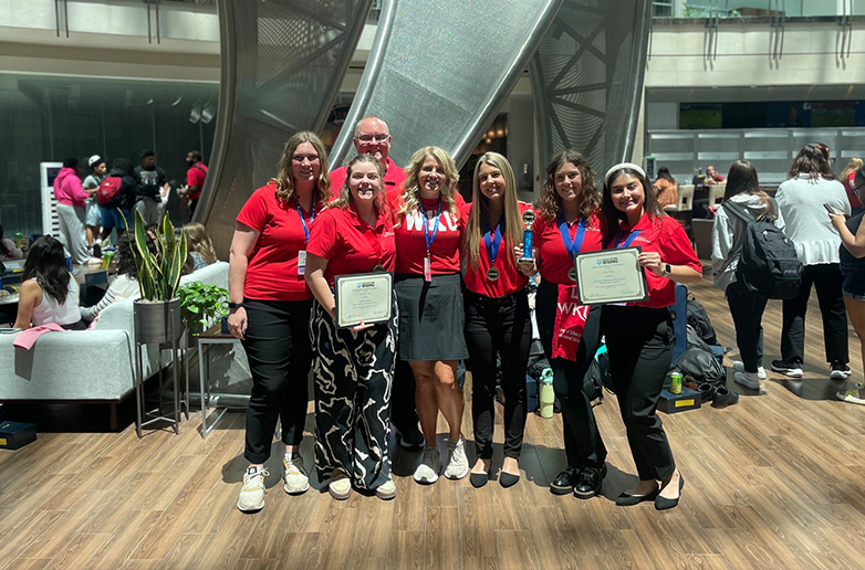 A group of WKU students and faculty from the College of Education and Behavioral Sciences pose with awards at a professional conference.