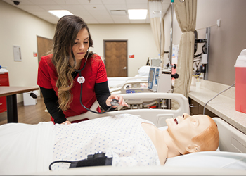 A WKU nursing student checks the heartbeat of a model of a person in class.