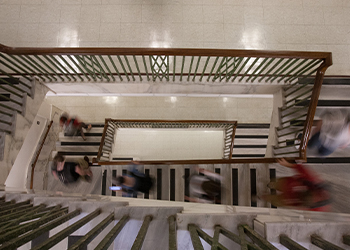 A top-down photo of a staircase in Cherry Hall with blurred people walking up and down the stairs.