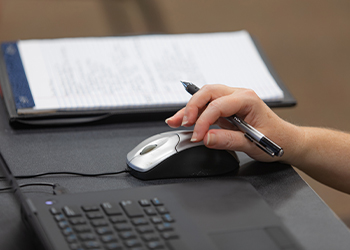 A person's hand hovers over a computer mouse.