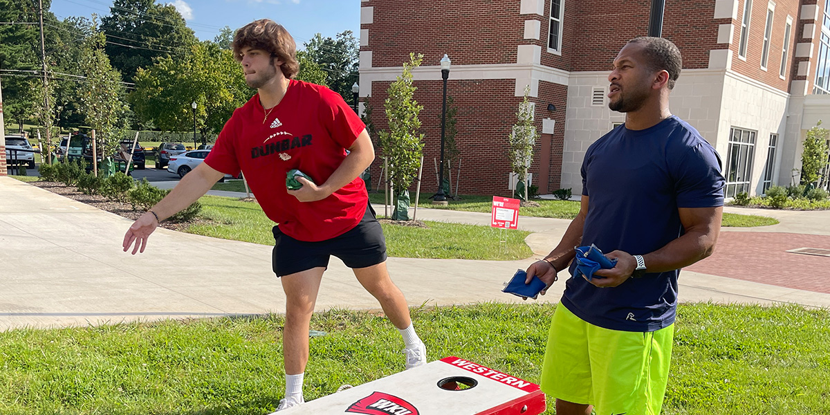 Student and professional playing cornhole