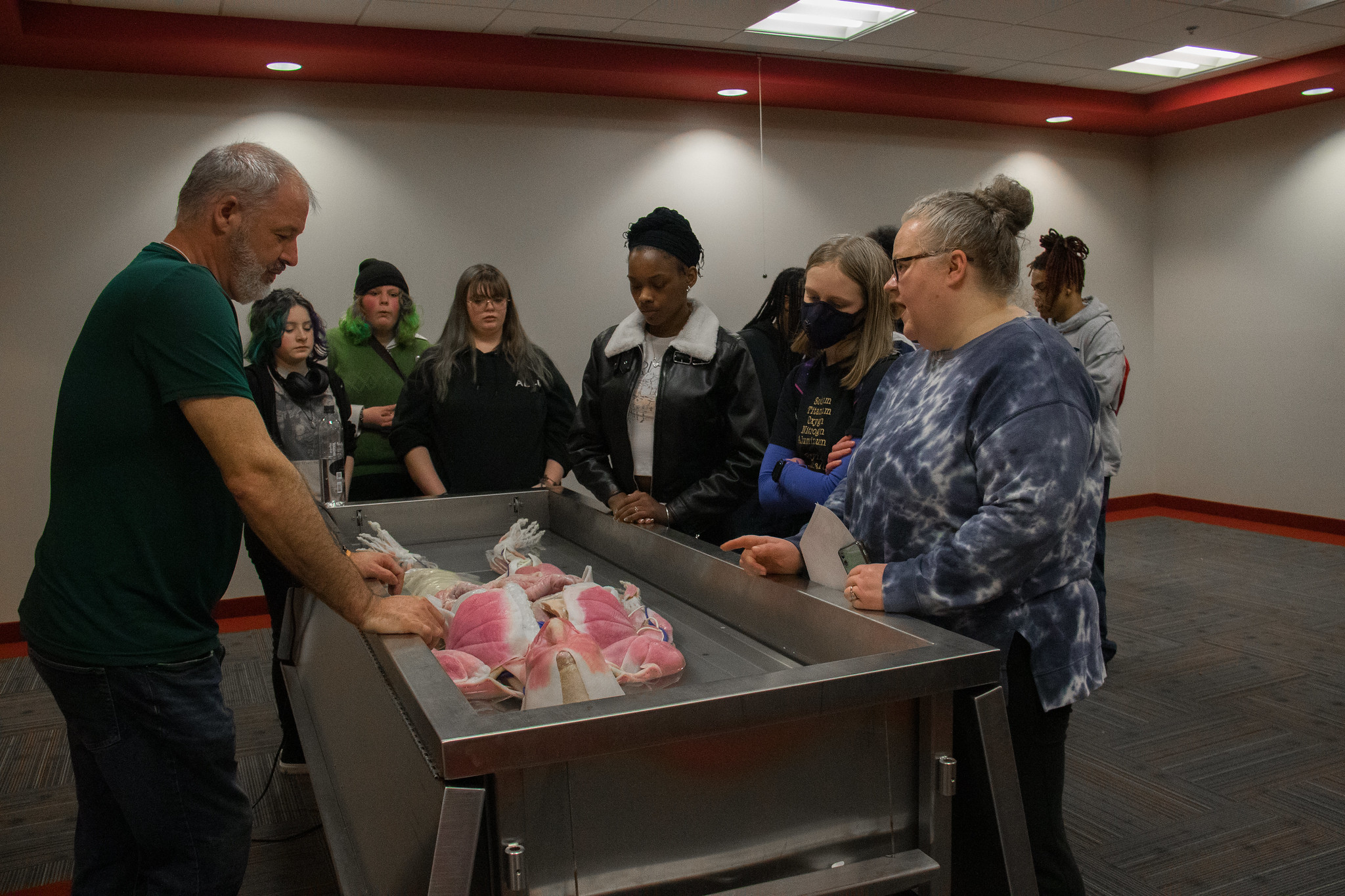 group of youth and adults gathered around a syn-daver, learning about anatomy