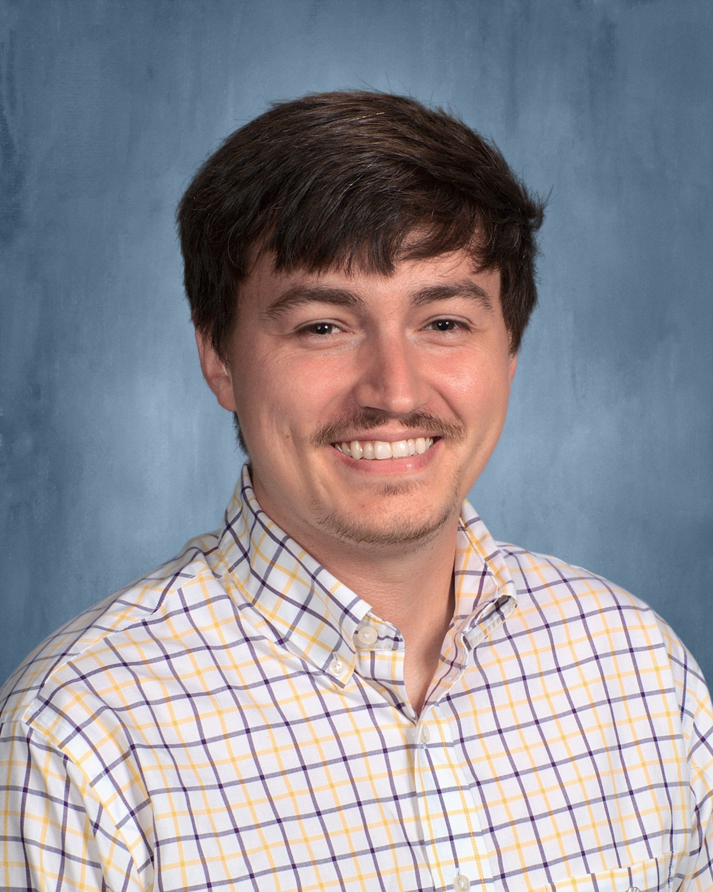 man in plaid shirt smiling at the camera