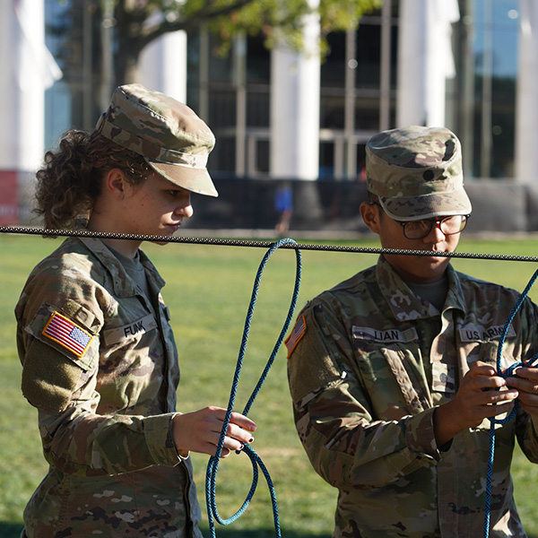 Two ROTC students in uniform set up a training exercise. 