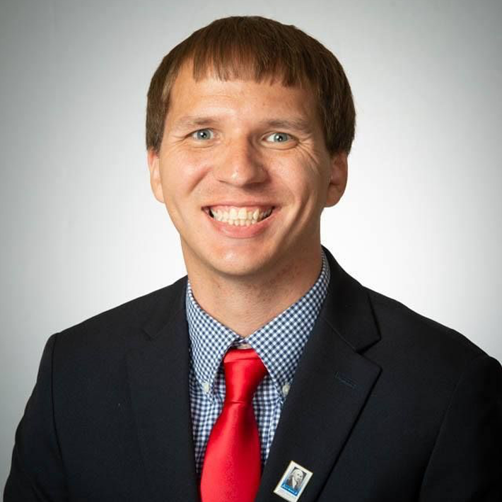 Kendrick Bryan smiling in a dark suit