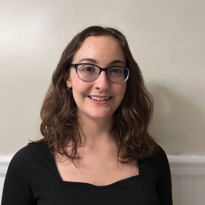 Woman with brown hair smiling in black shirt.