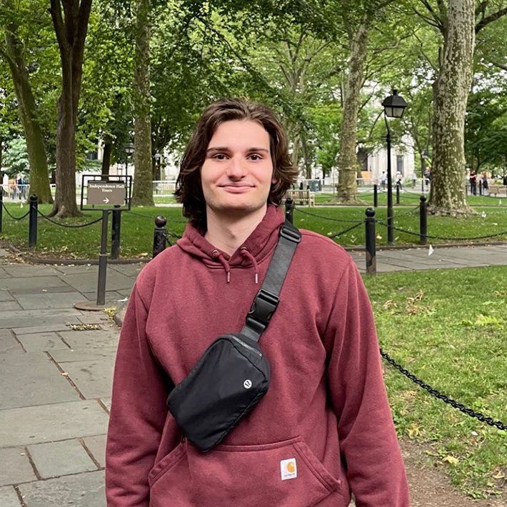 Man in hoodie standing in a green space.
