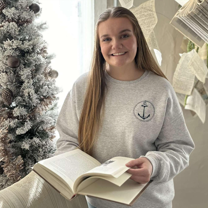 Woman smiling and holding a book as pages magically float behind her.