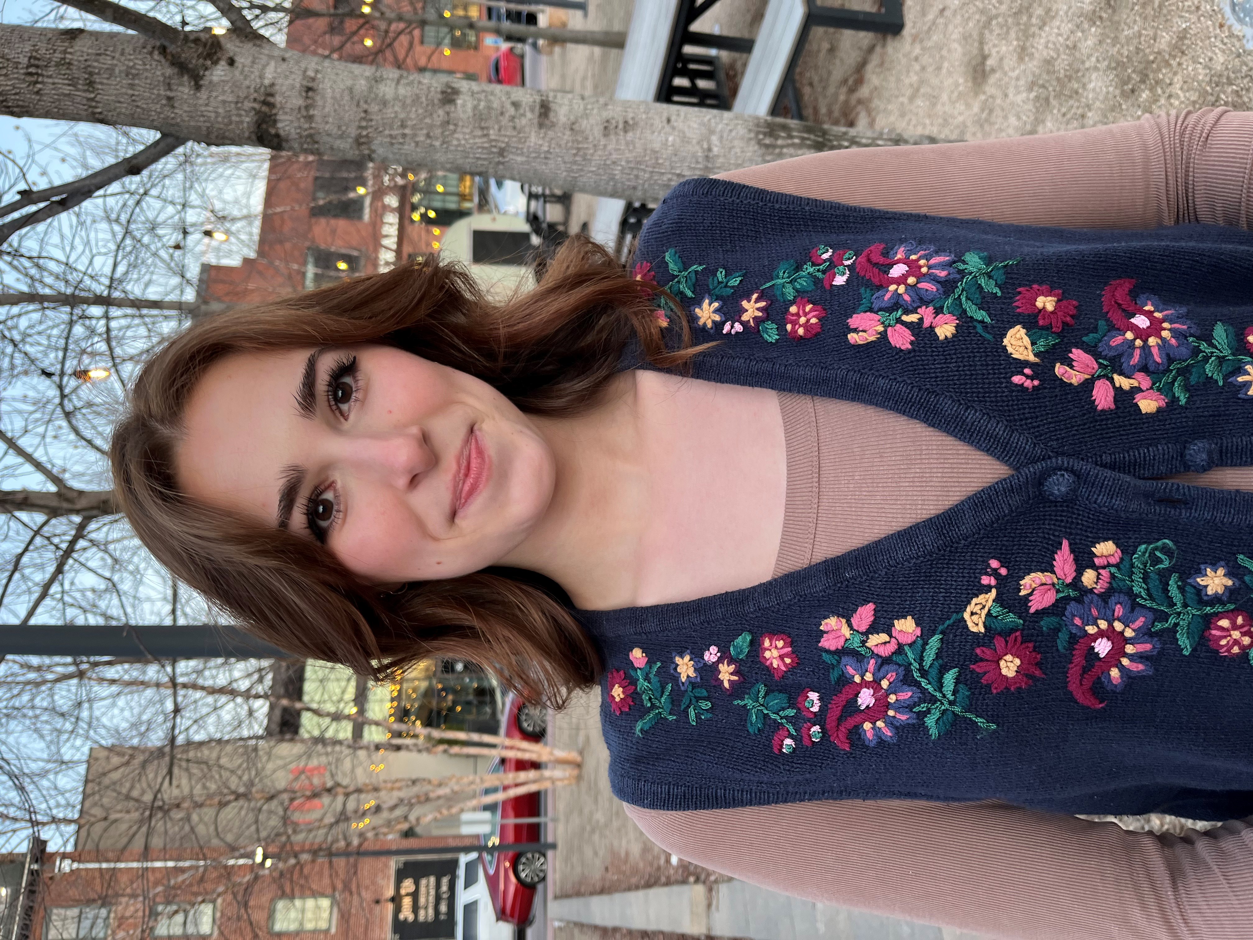 Red-headed college student wearing a vest smiling