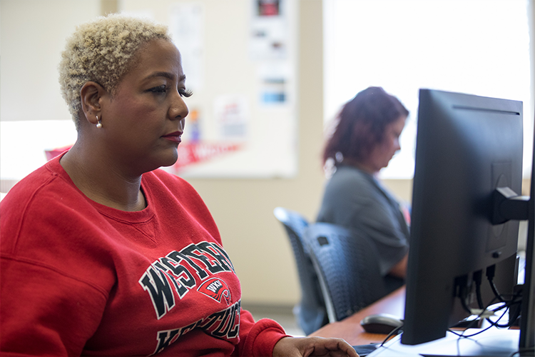 An individual sitting and typing in front of a computer