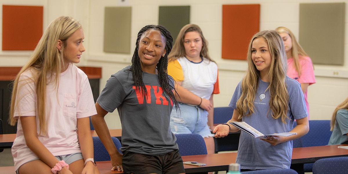 Three students smiling and talking in a group