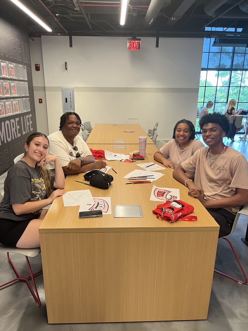 students sitting around a table smiling at the camera
