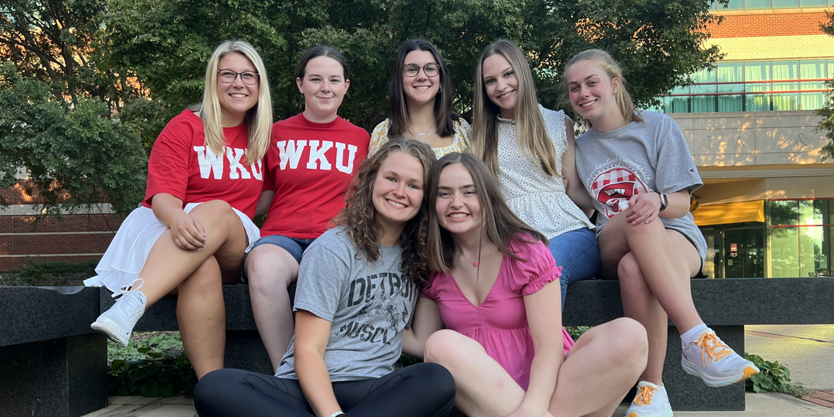 Group of girls smiling together outside on a bench