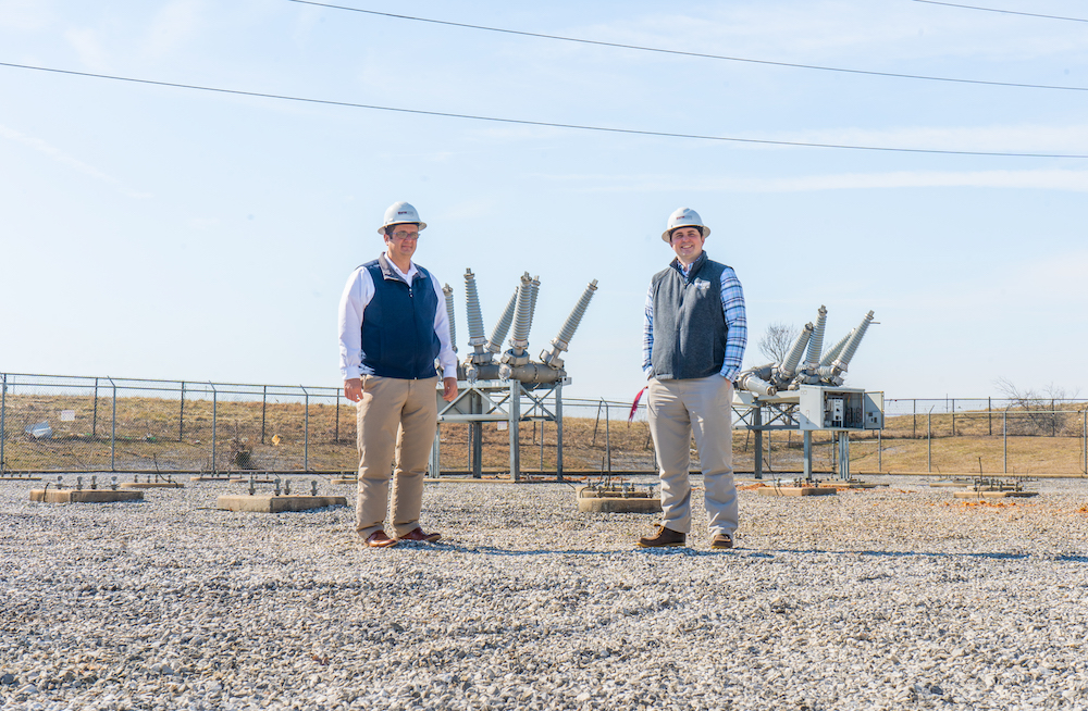 Two Warren Rural Elec Co-Op Corporation employees stand outside and smile.