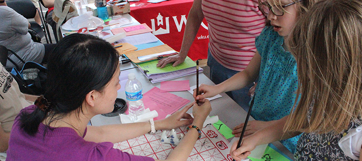 Student helping kids learn at event.