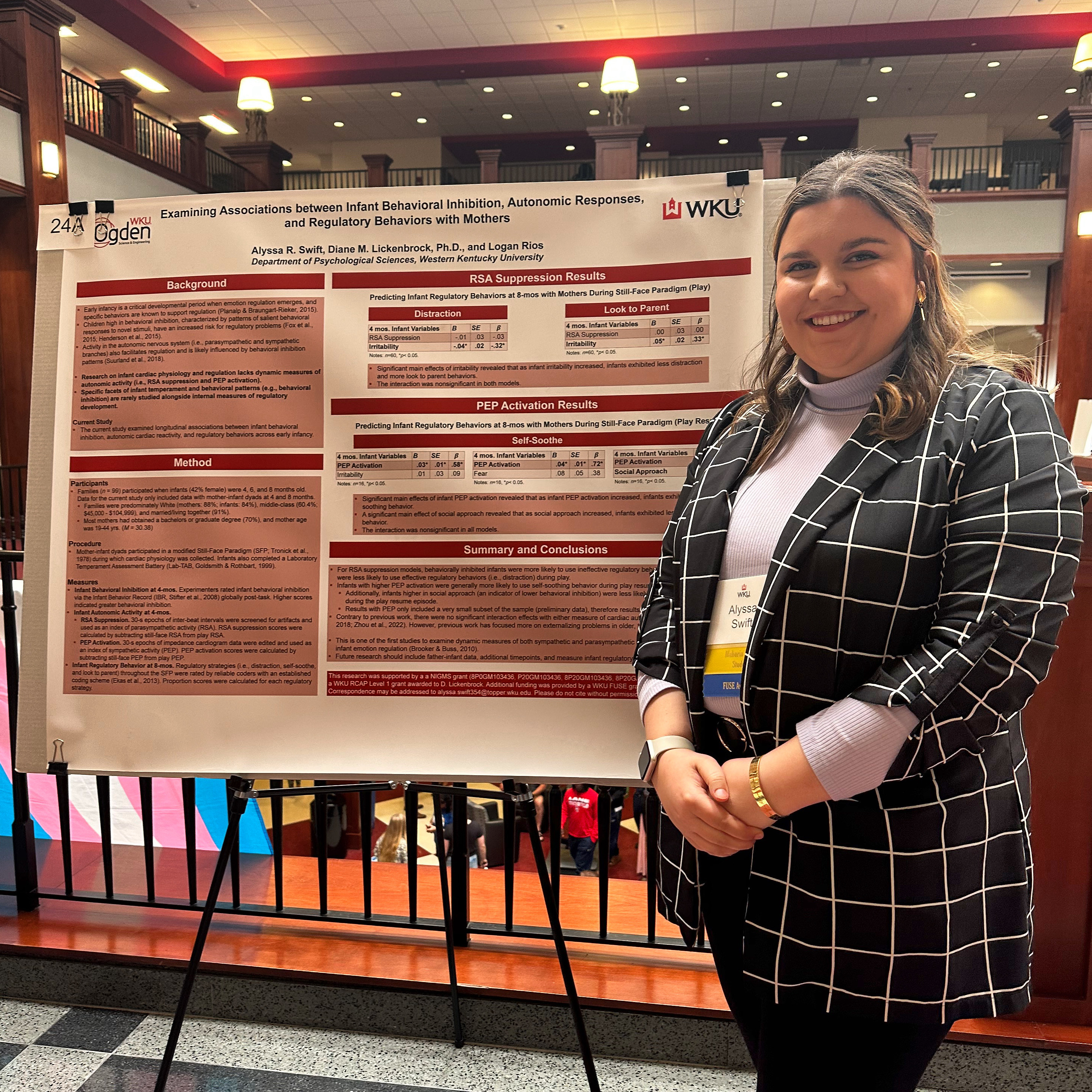Alyssa Swift smiles next to her research presentation poster.