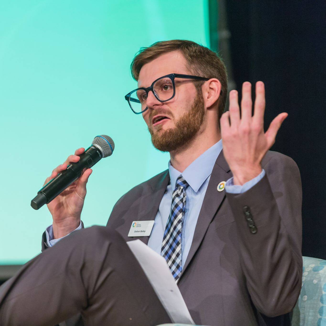 WKU Alumnu Dalton Bailey sits on a stage and speaks into a microphone..