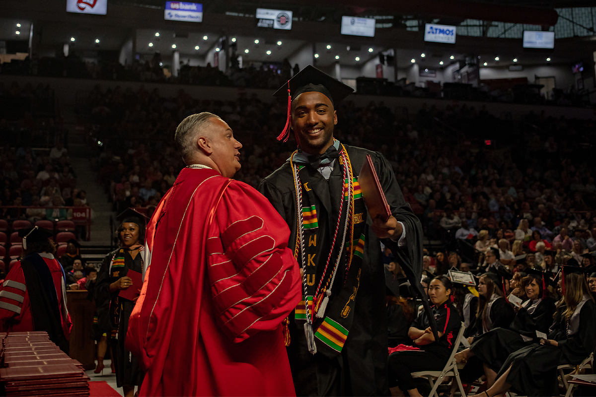 A student graduating during fall commencement with a degree in hand.