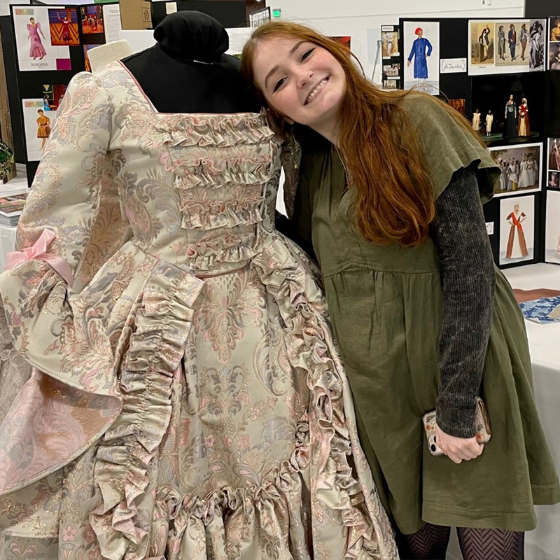 Woman standing with a stage costume dress.