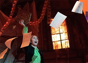 Woman singing as paper swirls around her.